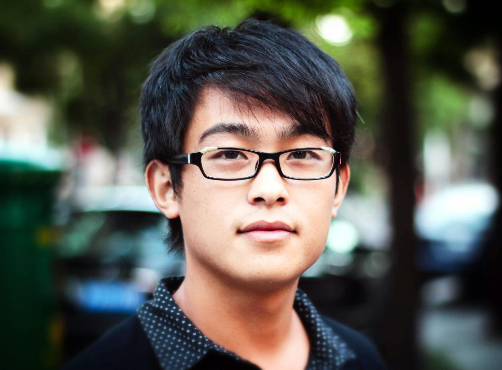 Young man standing on a street in Shanghai with a blurred background.